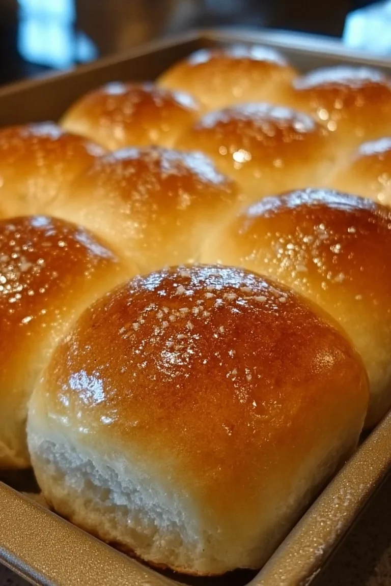Fluffy and soft homemade dinner rolls on a wooden serving board.