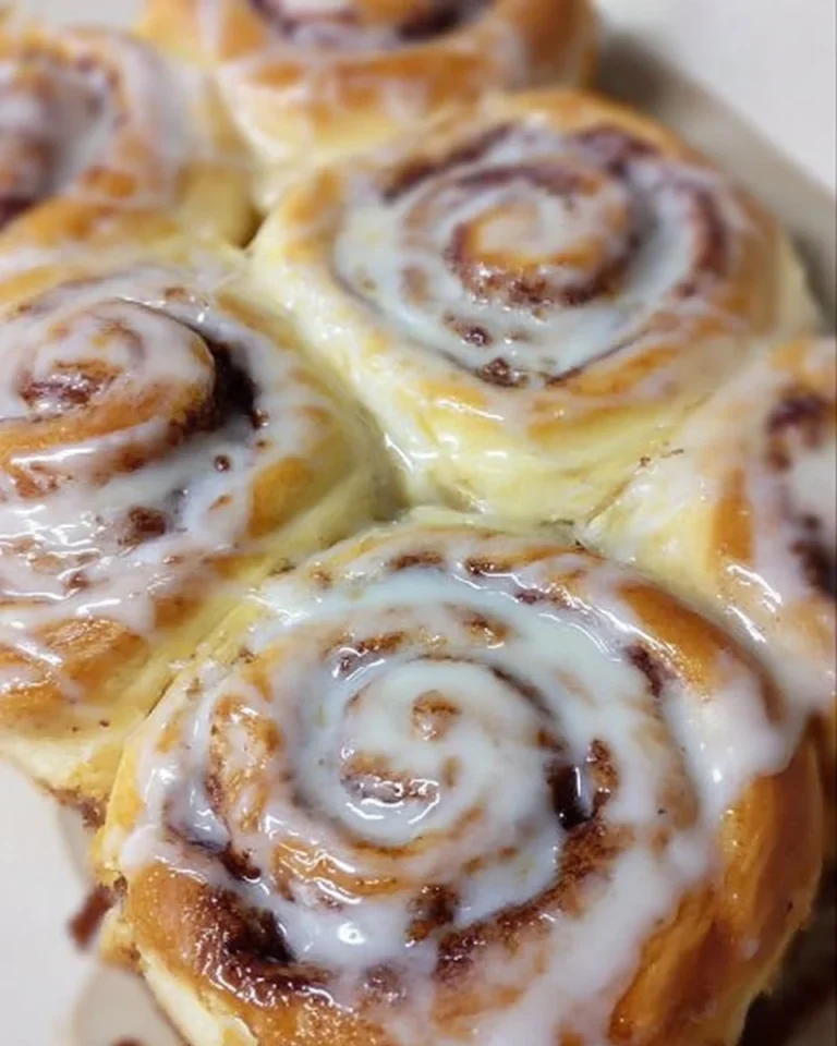 Freshly baked Bisquick cinnamon rolls topped with icing on a wooden table