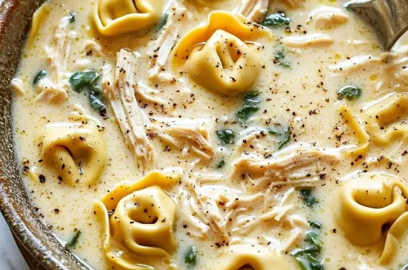 Bowl of creamy chicken tortellini soup garnished with herbs and served with crusty bread