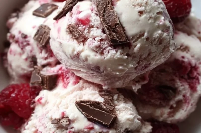 Bowl of easy raspberry chocolate chunk ice cream topped with fresh raspberries.