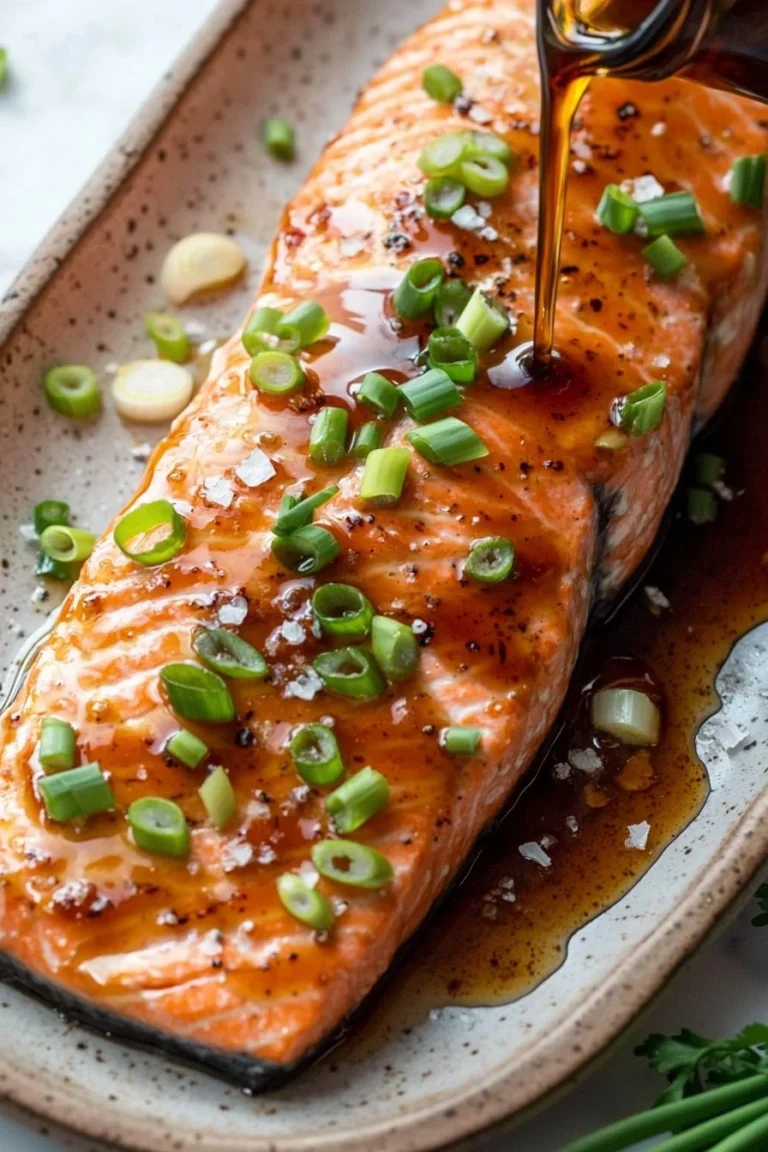 Maple Bourbon Glazed Salmon fillet served on a white plate with garnish.