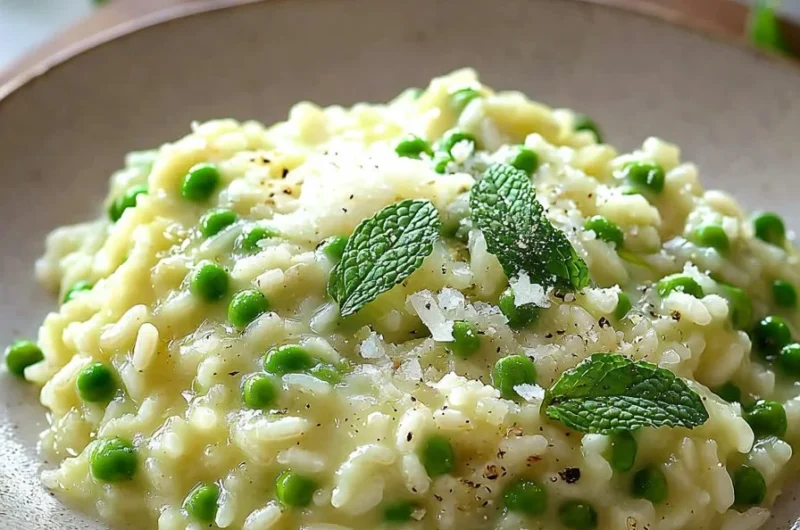 Creamy pea and mint risotto served in a bowl with fresh ingredients on the side.